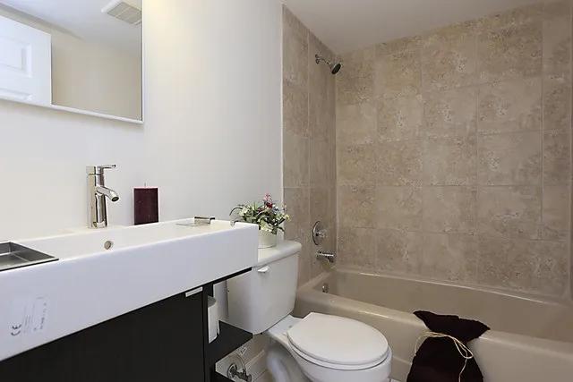 full bathroom with tiled shower / bath combo, toilet, and sink