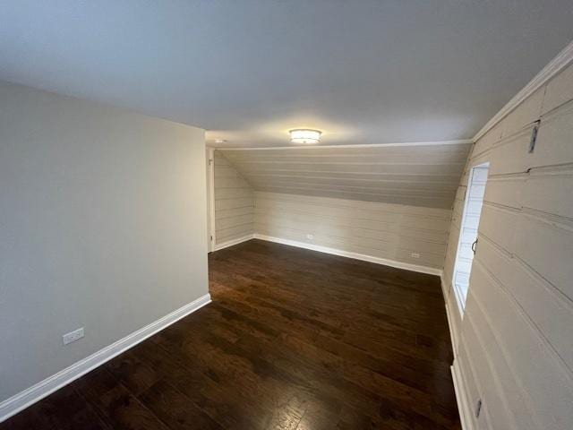 empty room with lofted ceiling, baseboards, and dark wood-type flooring