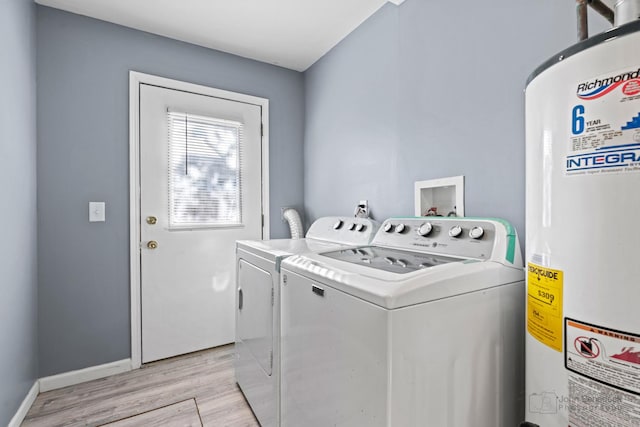 washroom with water heater, washer and clothes dryer, and light hardwood / wood-style flooring