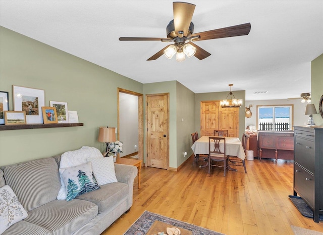 living room with ceiling fan with notable chandelier and light wood-type flooring