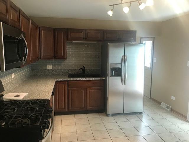 kitchen with light tile patterned floors, tasteful backsplash, visible vents, stainless steel appliances, and a sink