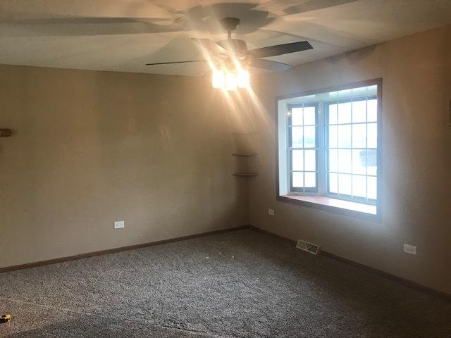 spare room featuring ceiling fan, carpet, visible vents, and baseboards