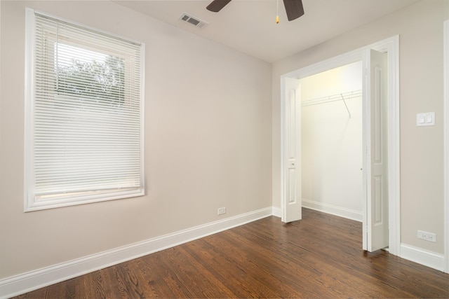 unfurnished bedroom with baseboards, visible vents, ceiling fan, dark wood-style flooring, and a closet