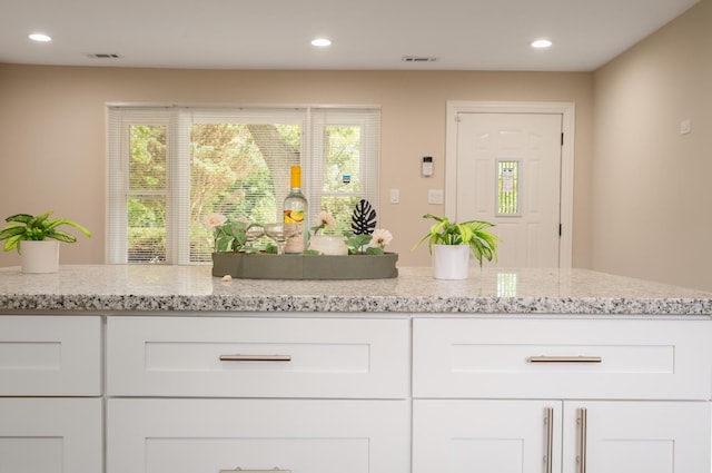 interior space with visible vents, white cabinetry, and light stone countertops