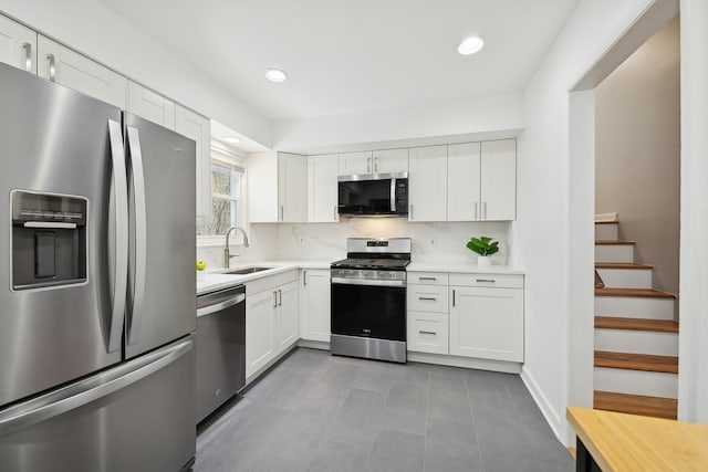 kitchen with tasteful backsplash, sink, light tile patterned floors, appliances with stainless steel finishes, and white cabinets