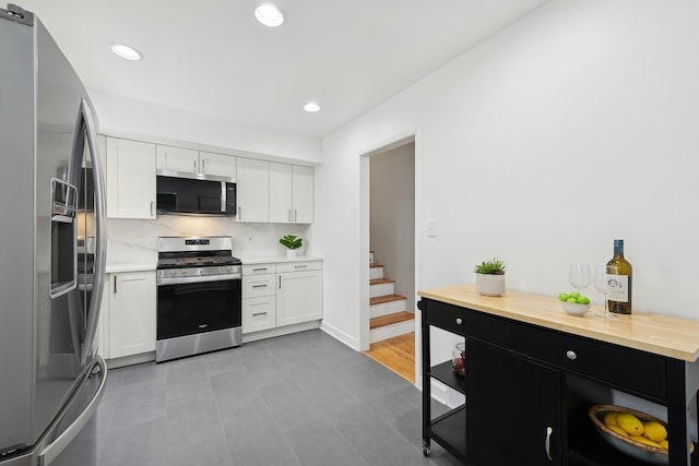 kitchen featuring light tile patterned flooring, white cabinets, appliances with stainless steel finishes, and tasteful backsplash