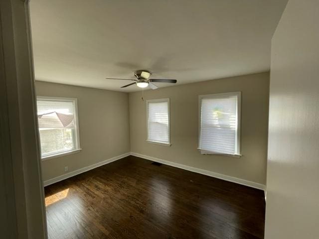 unfurnished room with dark wood-type flooring, ceiling fan, and baseboards