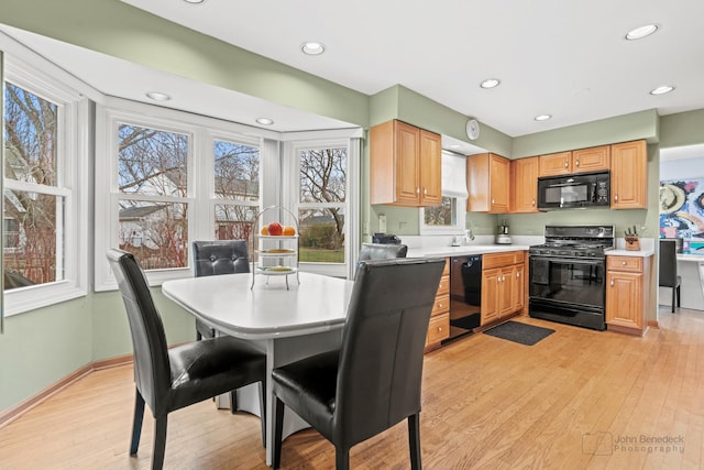 kitchen featuring light brown cabinetry, light wood-type flooring, and black appliances