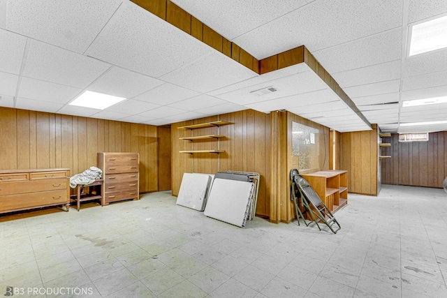 interior space featuring a paneled ceiling and wooden walls