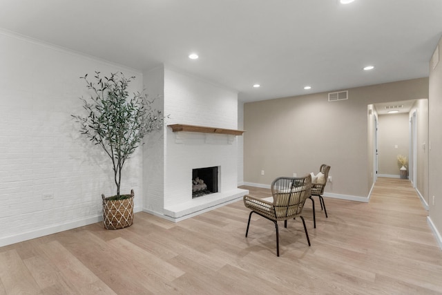 dining room featuring light hardwood / wood-style flooring, a brick fireplace, and crown molding