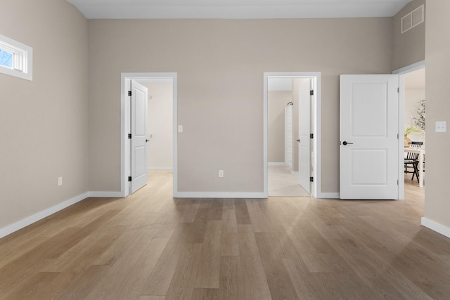 unfurnished bedroom with ensuite bath and light hardwood / wood-style flooring