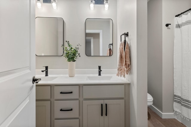 bathroom with walk in shower, hardwood / wood-style floors, vanity, and toilet