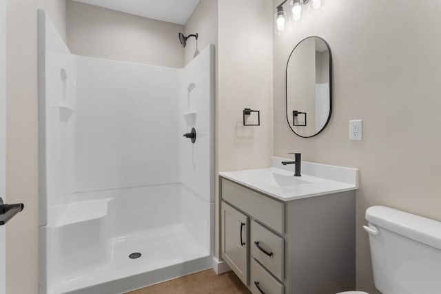 bathroom featuring hardwood / wood-style flooring, vanity, toilet, and a shower