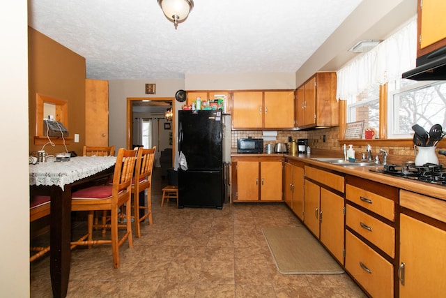 kitchen featuring sink, ventilation hood, backsplash, a textured ceiling, and black appliances