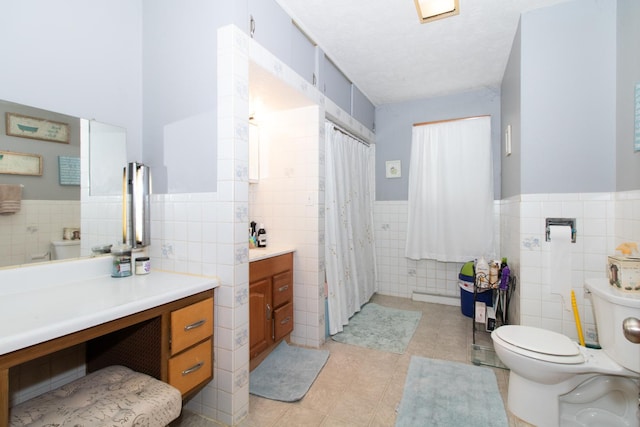 bathroom featuring tile patterned floors, vanity, tile walls, and toilet