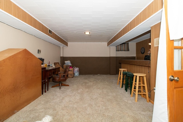 interior space featuring bar, light carpet, and wooden walls