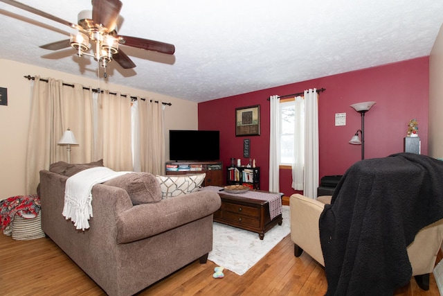 living room featuring ceiling fan, light hardwood / wood-style flooring, and a textured ceiling