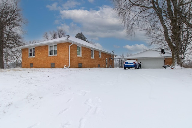 view of snowy exterior with an outbuilding and a garage