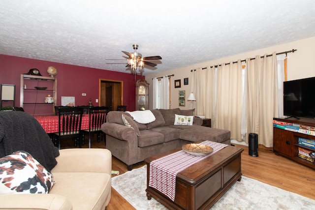 living room with a textured ceiling, light hardwood / wood-style floors, and ceiling fan