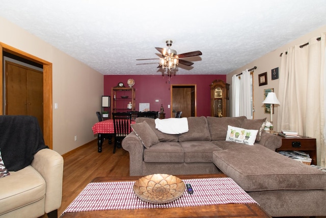 living room featuring ceiling fan, light hardwood / wood-style flooring, and a textured ceiling