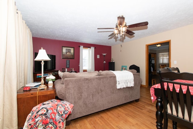 living room featuring a textured ceiling, light hardwood / wood-style floors, and ceiling fan