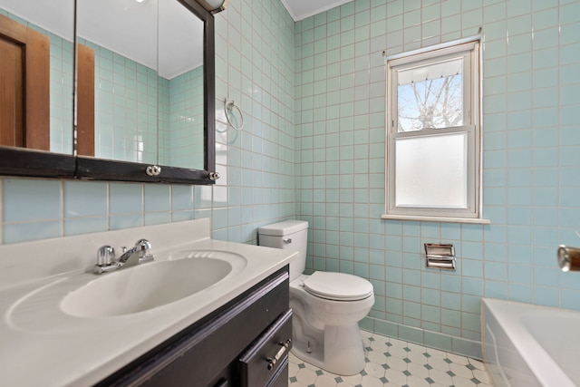 bathroom with a tub, vanity, tile walls, and toilet