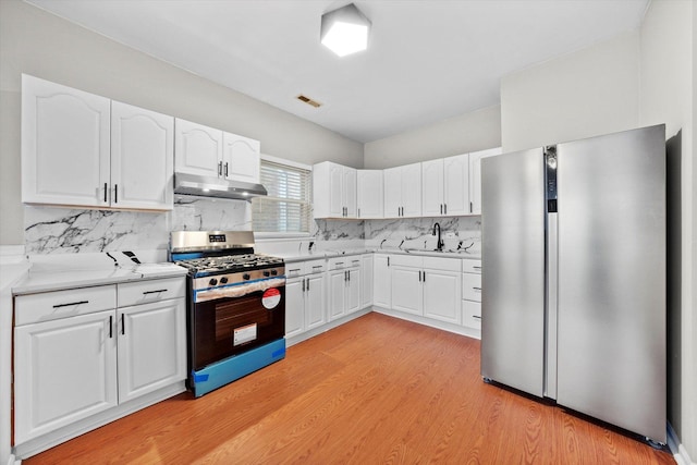 kitchen with white cabinets, appliances with stainless steel finishes, light hardwood / wood-style floors, and sink