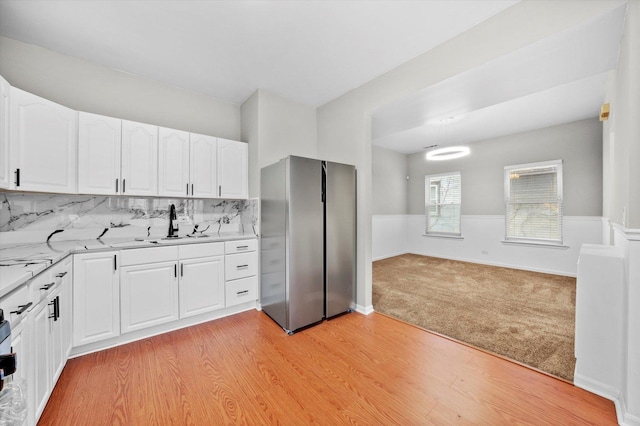 kitchen with light hardwood / wood-style floors, decorative backsplash, stainless steel fridge, and white cabinetry