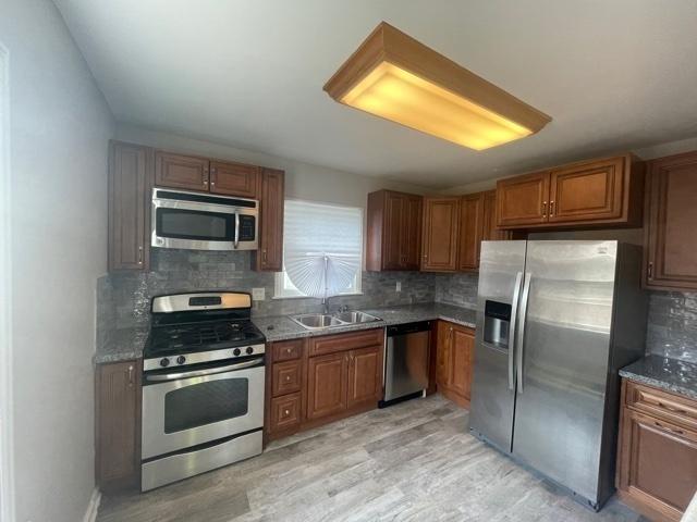 kitchen featuring appliances with stainless steel finishes, brown cabinetry, and backsplash