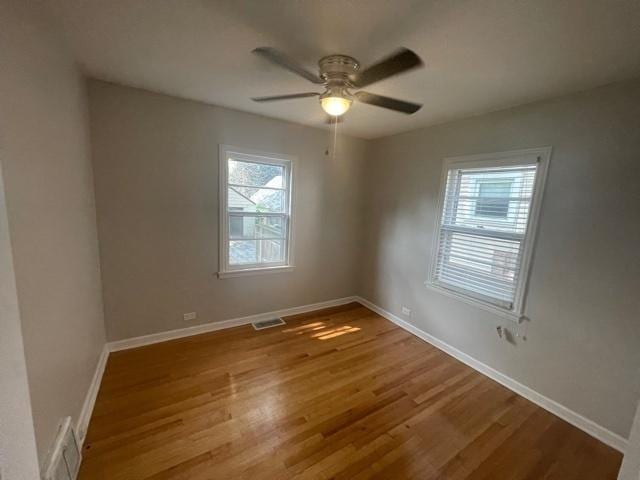 empty room featuring light wood-style floors, visible vents, baseboards, and ceiling fan