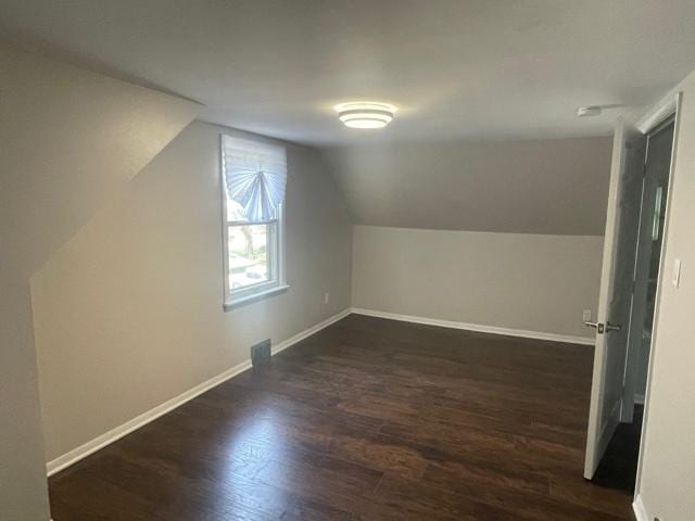 additional living space featuring lofted ceiling, baseboards, and dark wood finished floors