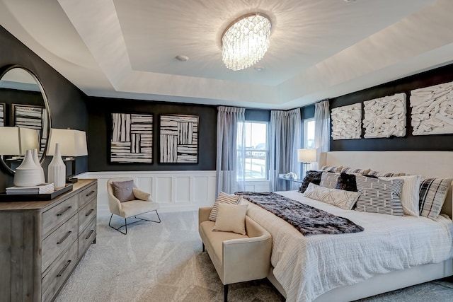 carpeted bedroom with a raised ceiling and a chandelier