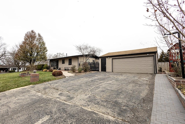 ranch-style home featuring a garage, an outdoor structure, and a front yard