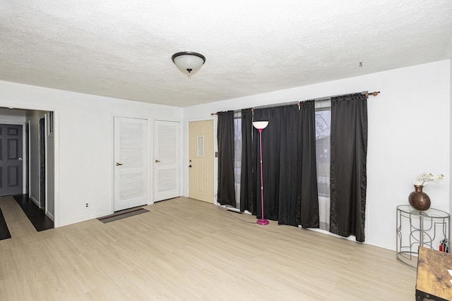 unfurnished bedroom with multiple closets, hardwood / wood-style floors, and a textured ceiling