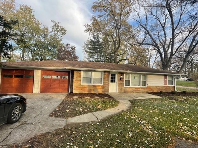 ranch-style home featuring an attached garage, aphalt driveway, and a front yard