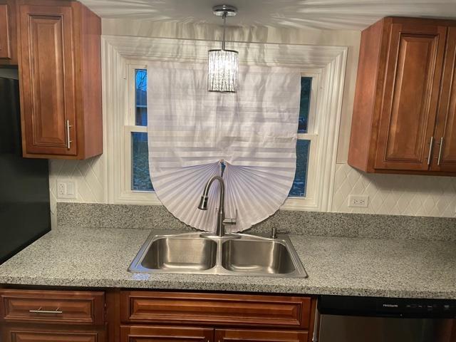 kitchen with dishwasher, black fridge, a sink, and brown cabinets