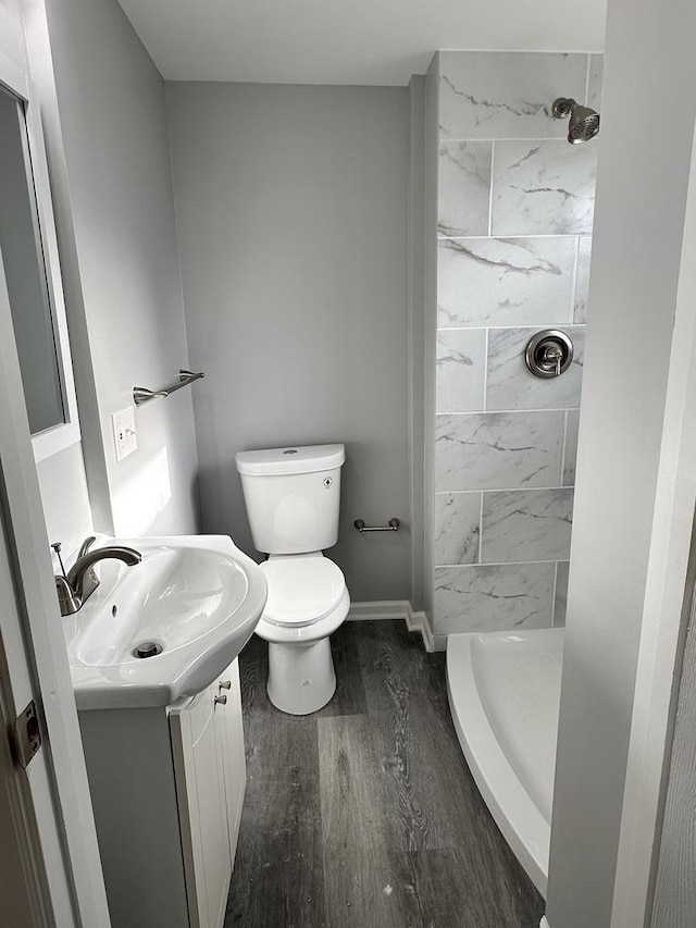 bathroom with a tile shower, toilet, vanity, and hardwood / wood-style flooring