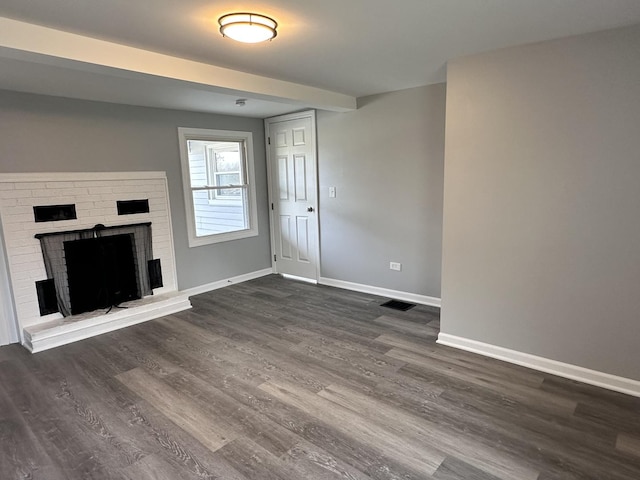 unfurnished living room featuring beam ceiling, dark hardwood / wood-style flooring, and a fireplace