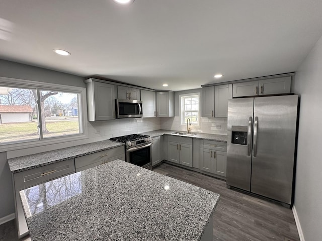 kitchen with tasteful backsplash, light stone counters, dark hardwood / wood-style floors, and appliances with stainless steel finishes