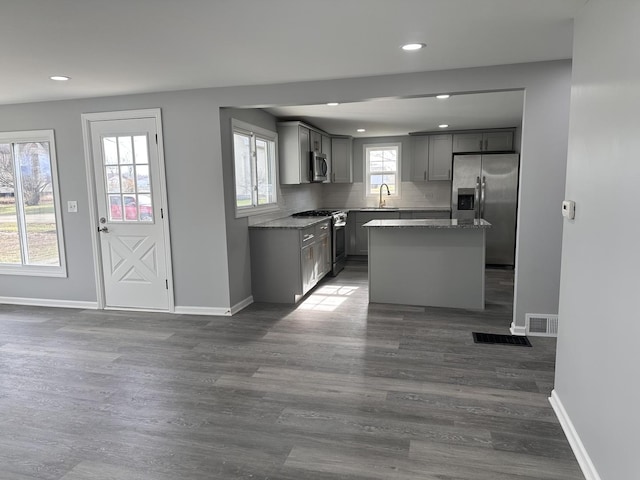 kitchen featuring stainless steel appliances, dark wood-type flooring, sink, a center island, and gray cabinets