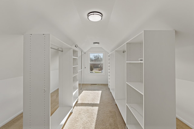 walk in closet featuring light colored carpet and lofted ceiling