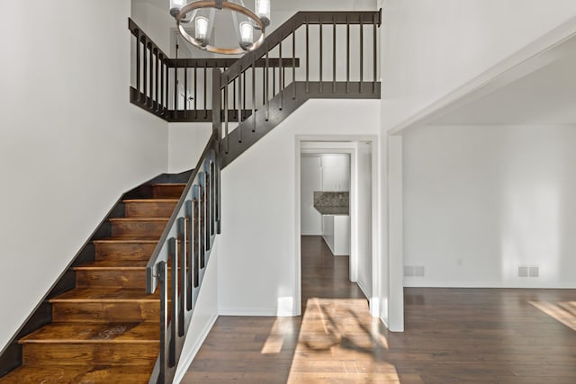 stairway featuring a towering ceiling, a chandelier, and hardwood / wood-style flooring