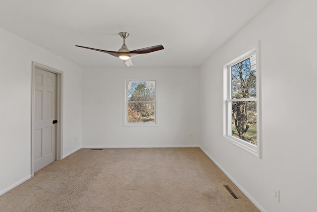 empty room featuring light carpet, ceiling fan, and a healthy amount of sunlight