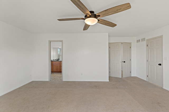 unfurnished bedroom with ensuite bathroom, ceiling fan, and light carpet