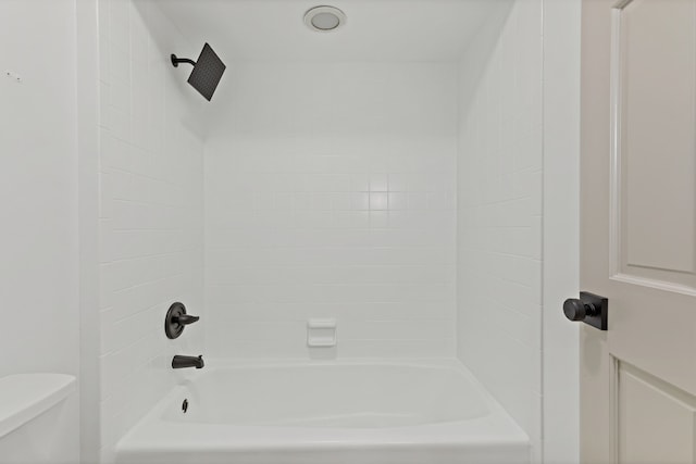 bathroom featuring tiled shower / bath combo and toilet