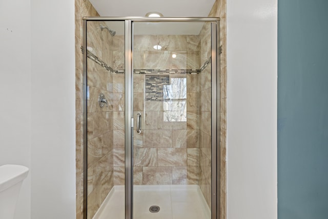 bathroom featuring toilet and a shower with shower door