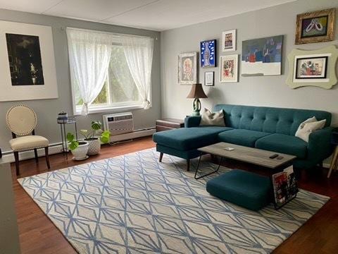 living area with a wall mounted air conditioner, a baseboard heating unit, and hardwood / wood-style flooring