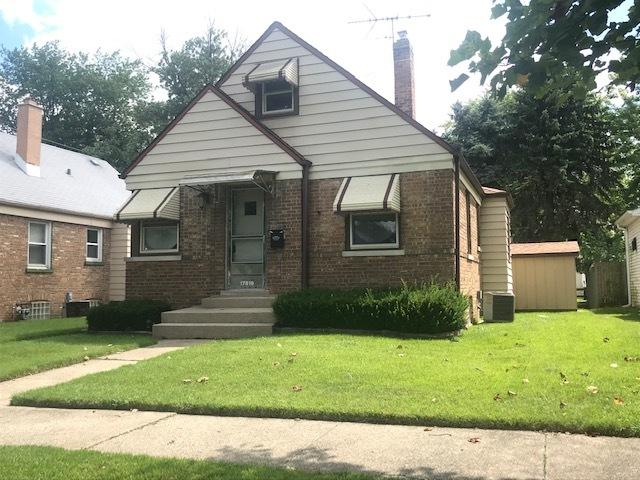 bungalow featuring brick siding, a chimney, and a front lawn