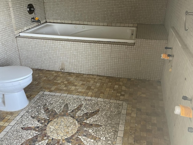 bathroom featuring a relaxing tiled tub and toilet