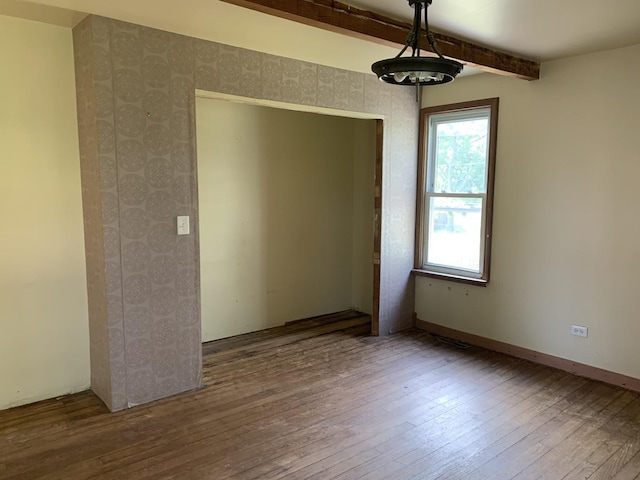 empty room featuring hardwood / wood-style floors and beamed ceiling